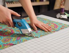 Tailor using battery powered fabric scissors to cut precise patterns on colorful fabric
