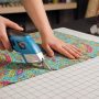 Tailor using battery powered fabric scissors to cut precise patterns on colorful fabric