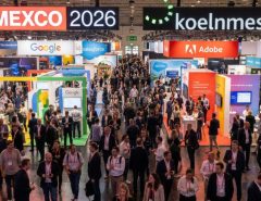 Thousands of digital marketing professionals networking on the busy exhibition floor at DMEXCO 2026 inside Koelnmesse in Cologne, Germany, with branded exhibitor booths lining the halls
