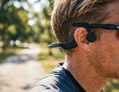Woman wearing bone conduction headphones while running outdoors.