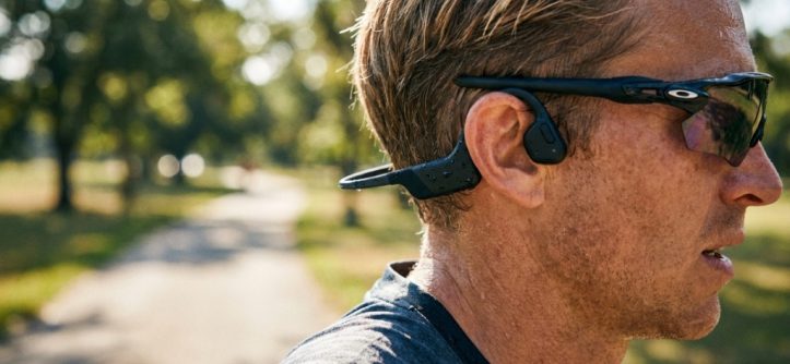 Woman wearing bone conduction headphones while running outdoors.