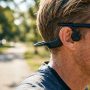 Woman wearing bone conduction headphones while running outdoors.